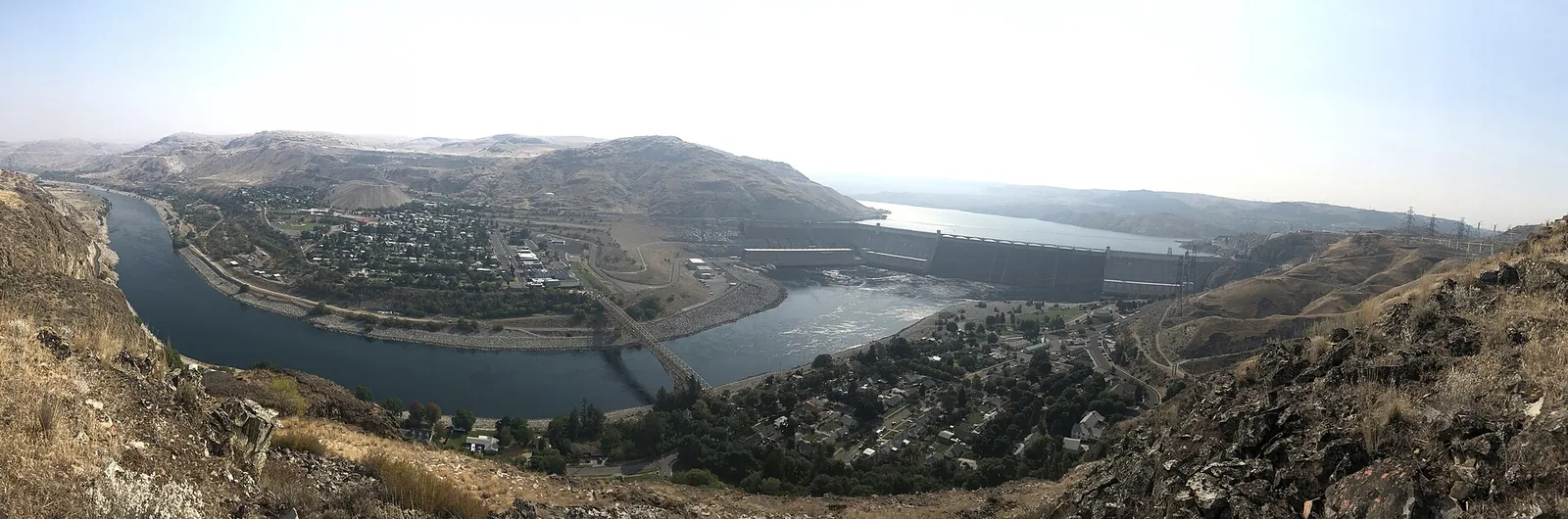 Panoramic view of Grand Coulee Dam, the river, nearby settlement and dry rocky hills