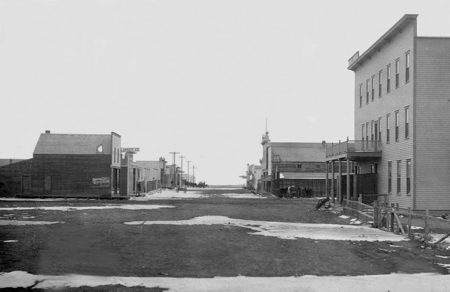 Historic Bow Island street with wooden commercial buildings, an unpaved road and open prairie at the horizon