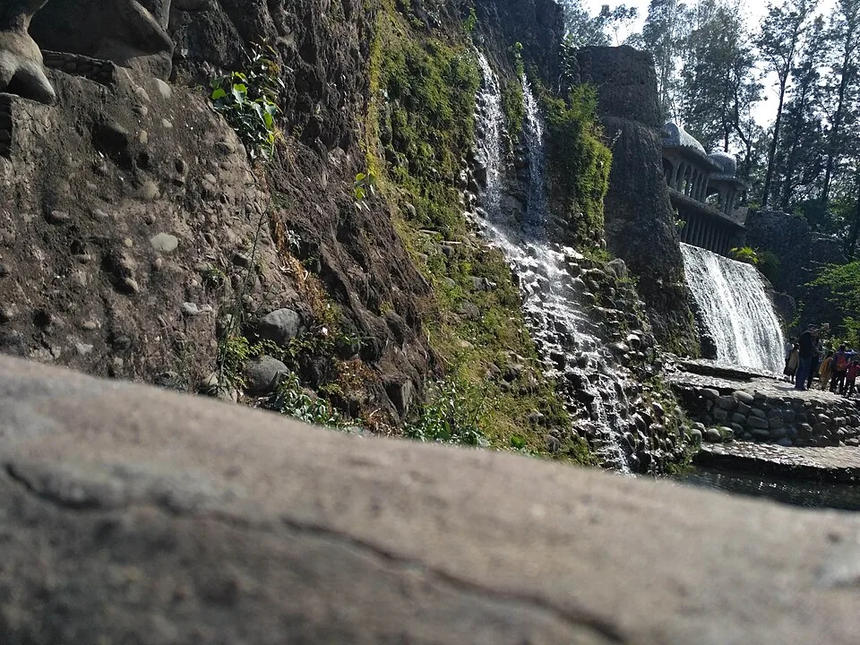 Water falling over the dark constructed rock walls of Nek Chand’s garden