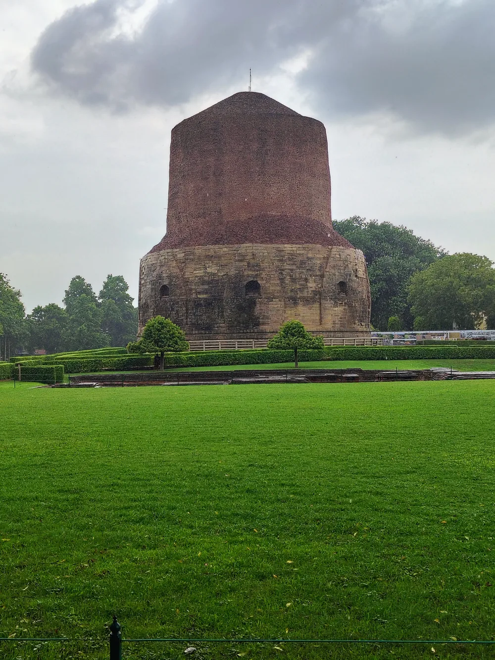 The cylindrical brick Dhamek Stupa at Sarnath with carved stone band, against a pale sky