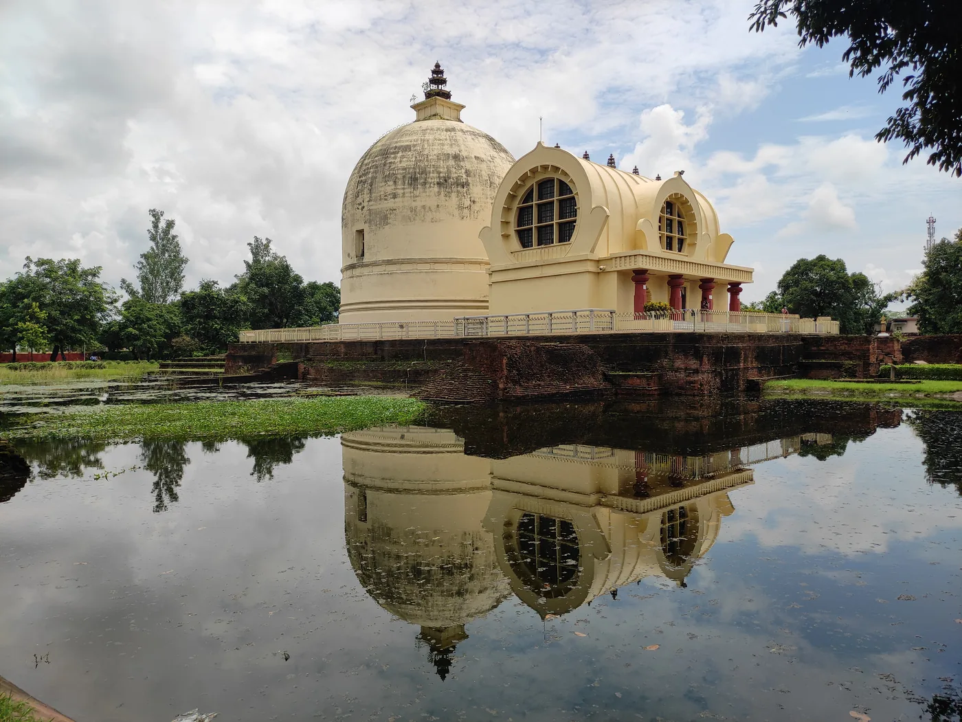 The white domed Parinirvana Stupa and temple at Kushinagar set in a lawn with trees