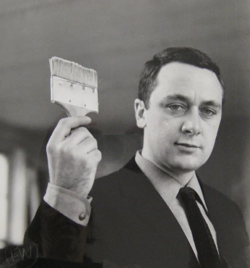Black-and-white photograph of the young Gerhard Richter in a dark jacket, looking down at a print in a workshop