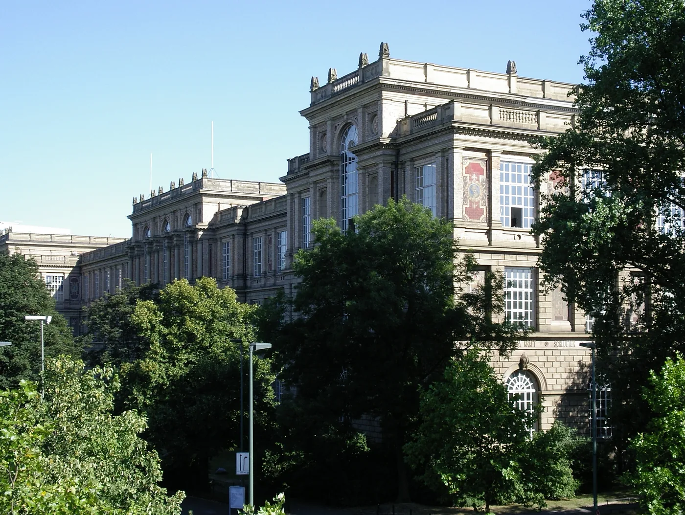 The long neoclassical façade of the Kunstakademie Düsseldorf beside the Rhine, under a bright sky