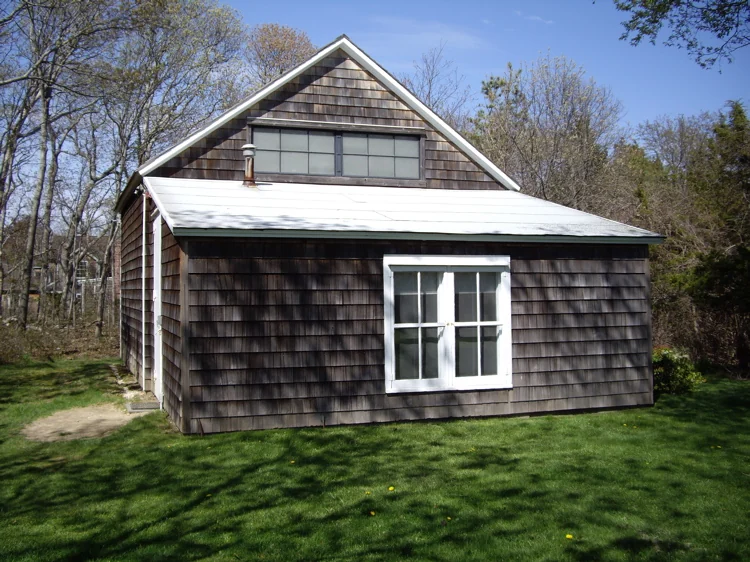 A small weathered timber barn with a pitched roof among trees in Springs, New York