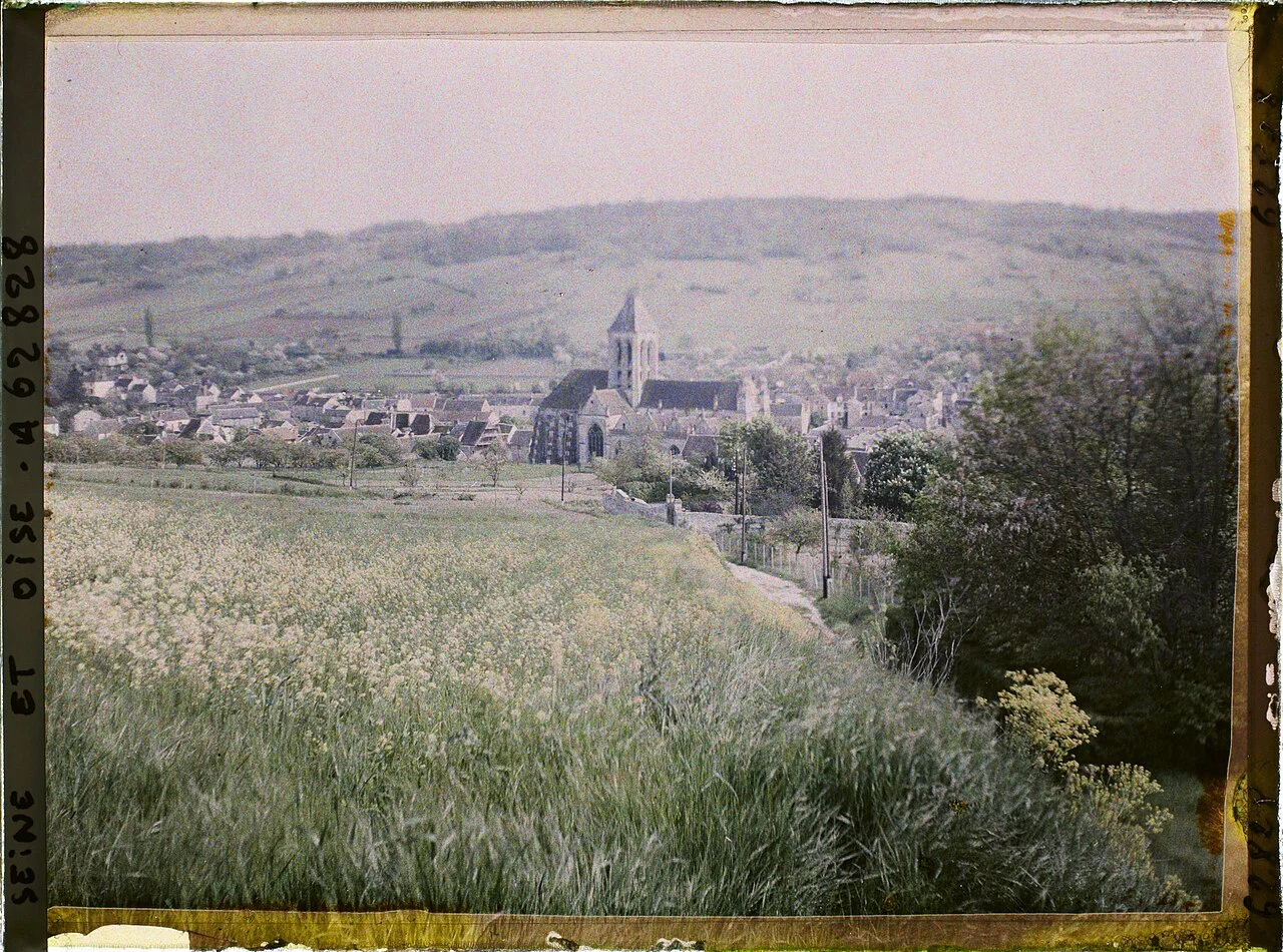 Vétheuil’s church and village across a meadow in a 1930 colour photograph.