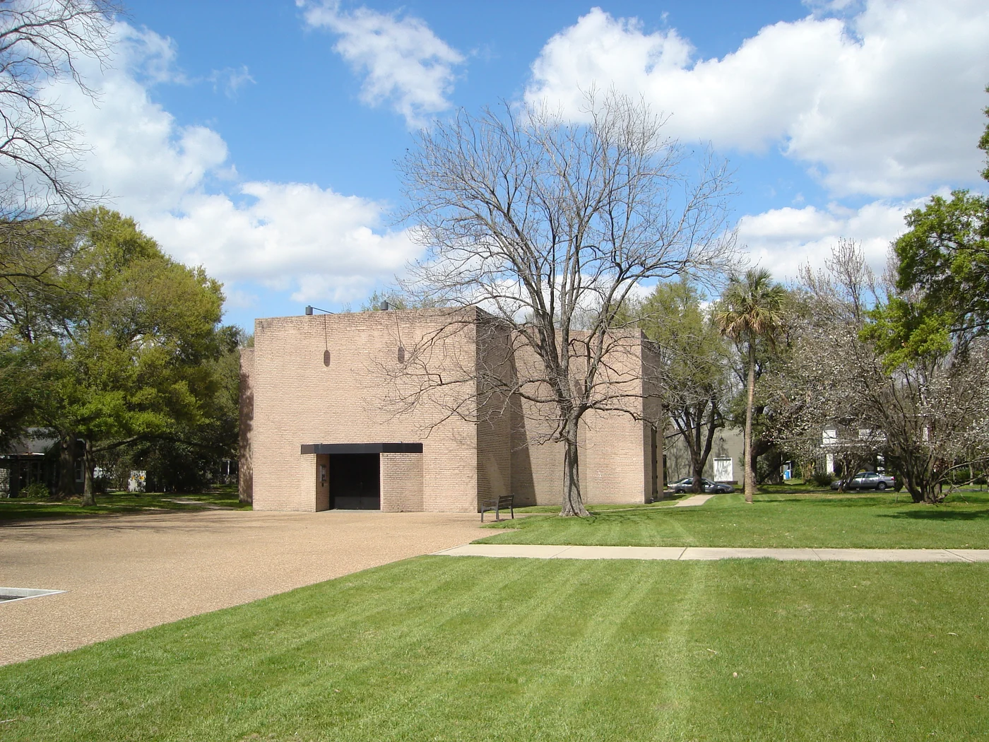 Low brick walls and pale angular roof of the Rothko Chapel beside trees in Houston